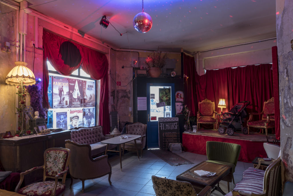 Inside B-ware! Ladenkino's bar. A disco ball hangs from the ceiling and armchairs are scattered around tables.