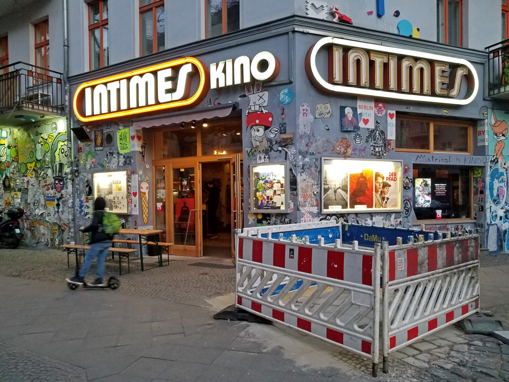Entrance to Intimes Kino. Its entrance is covered in graffit and stickers, and film posters are also displayed on the walls.