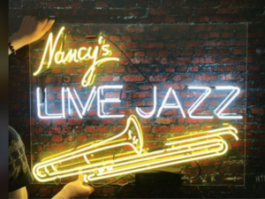 An illuminated neon sign of the sign of Nancy Tilitz Galerie which writes Nancy's Live Jazz