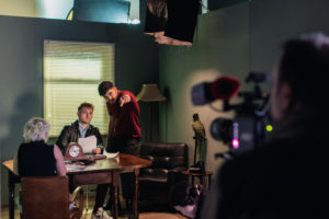 Three BIMM University Berlin students sitting at a table acting, with someone recording them with a camera