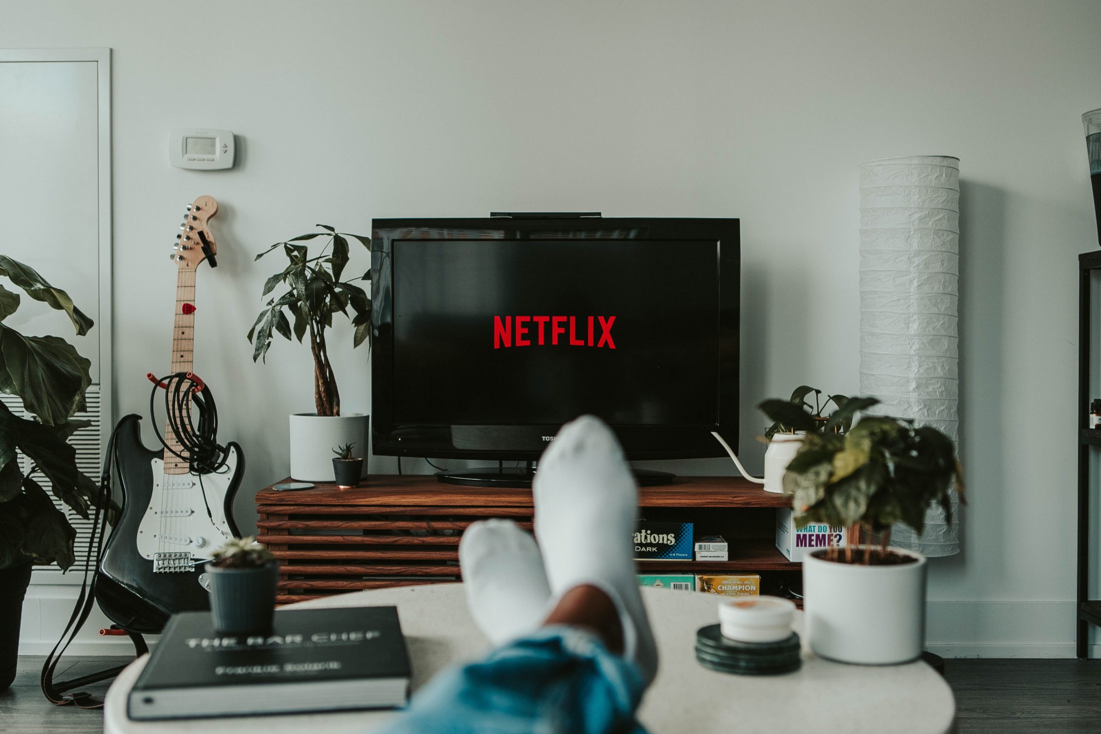 Persons feet up, while TV in the background display Netflix on the TV