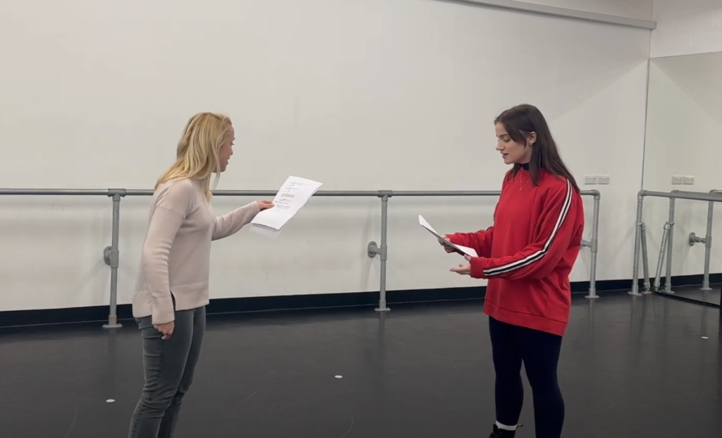 Emily and her mentor perform a scene. they're holding scripts