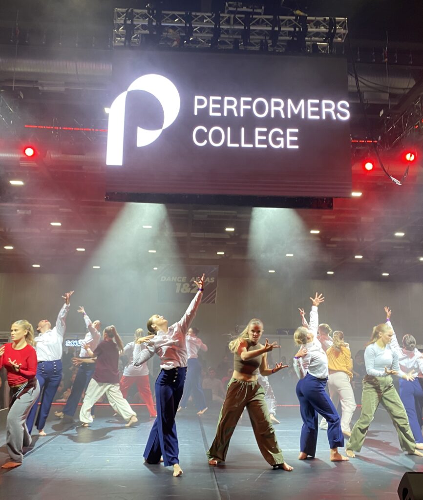 Amelia Dances at a large event under a huge performers college sign
