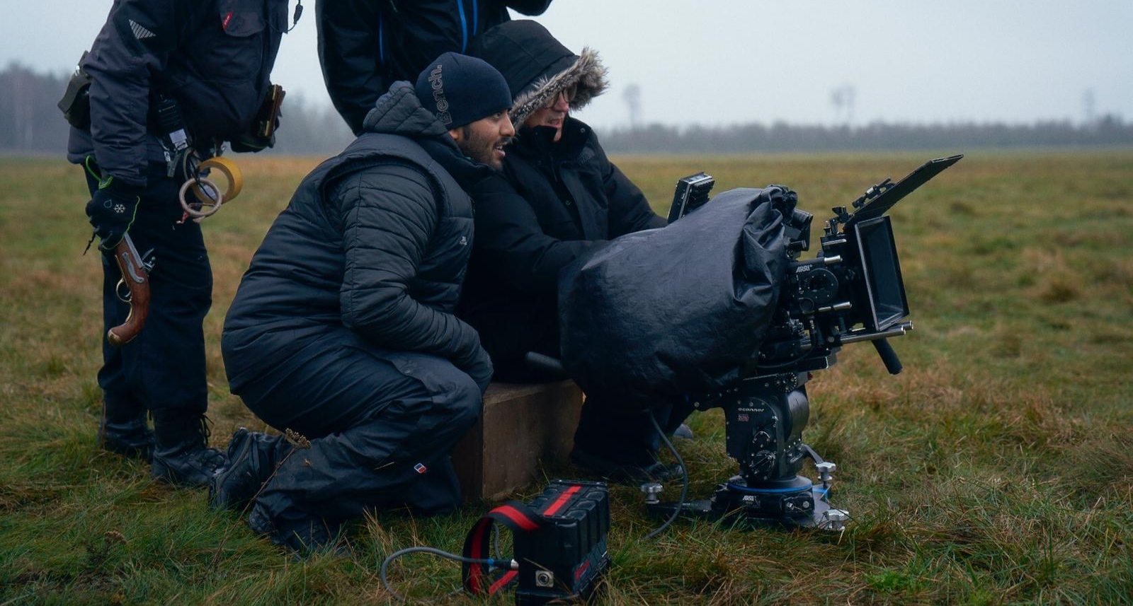 director akaash meeda on set, kneeling by camera