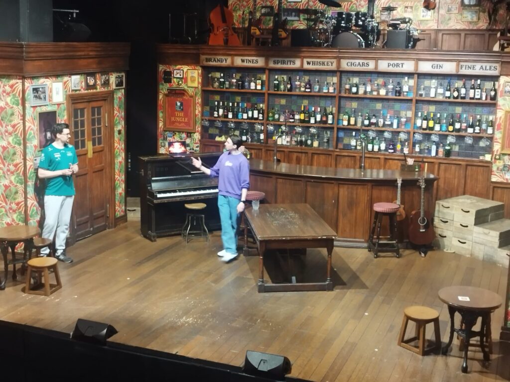 Adam directs a cast member on stage in choir of man