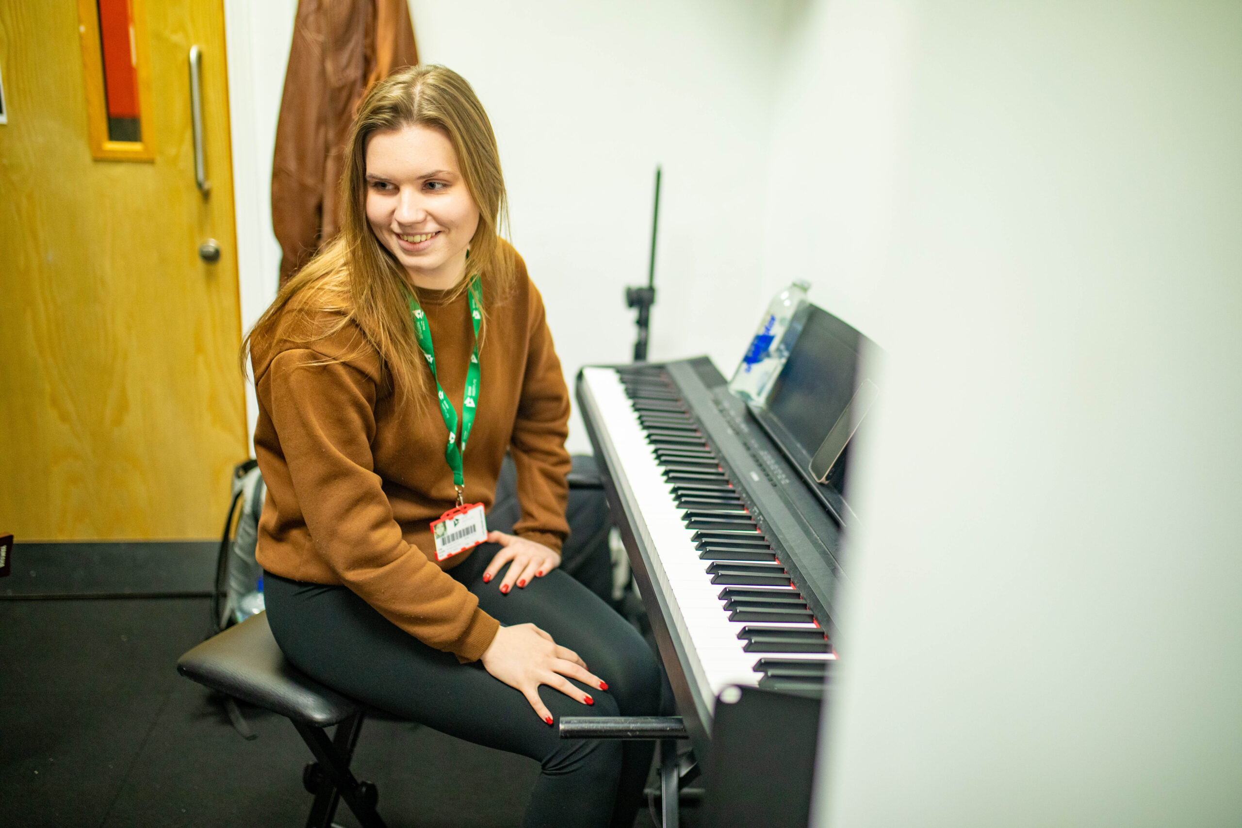 Female student sitting next to an electric piano